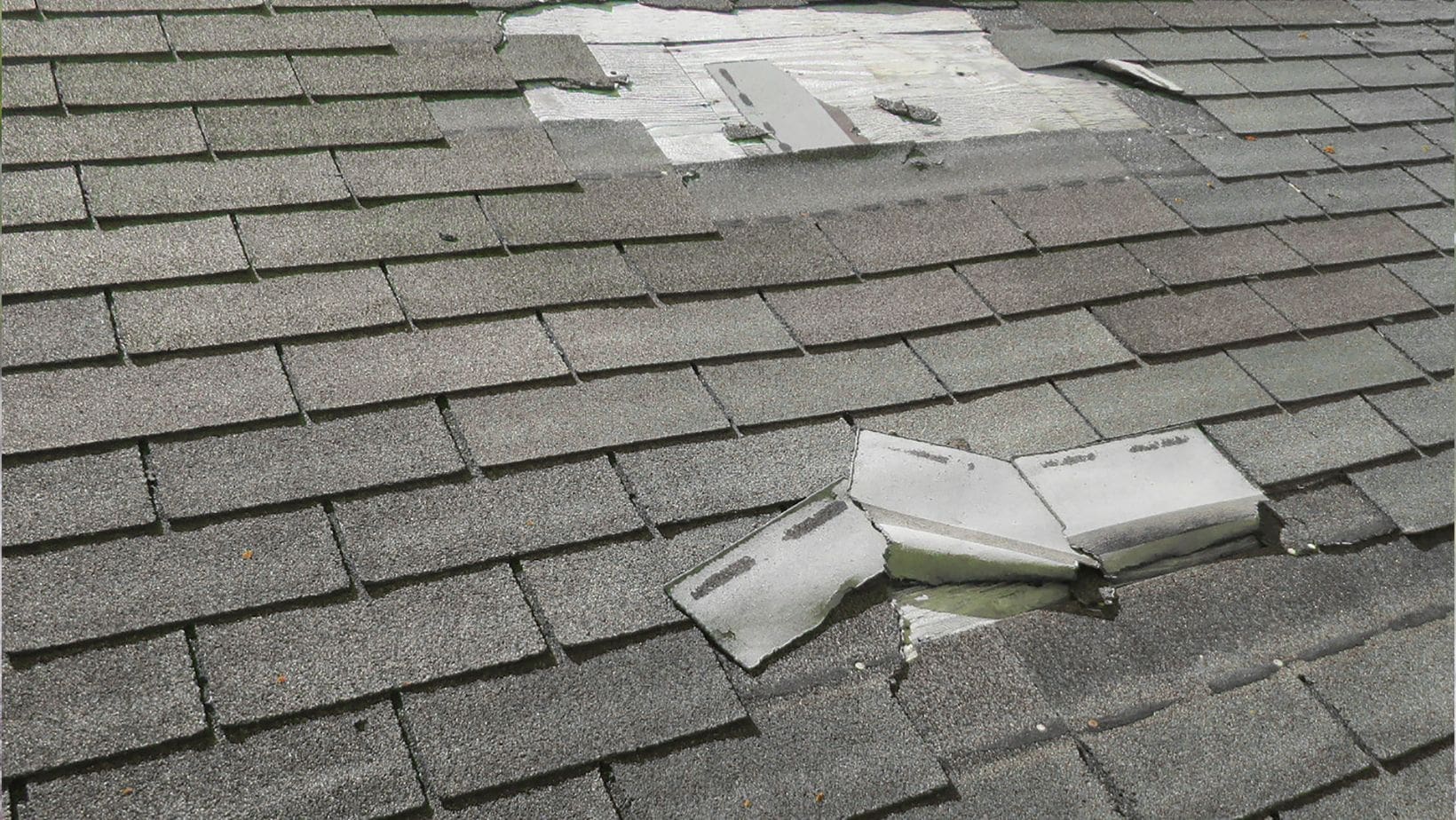 A residential roof with visible wind damage, including missing or lifted shingles. Empire Contractors LLC provides expert wind-damaged roof repair and replacement services in Cincinnati, OH, and surrounding areas.