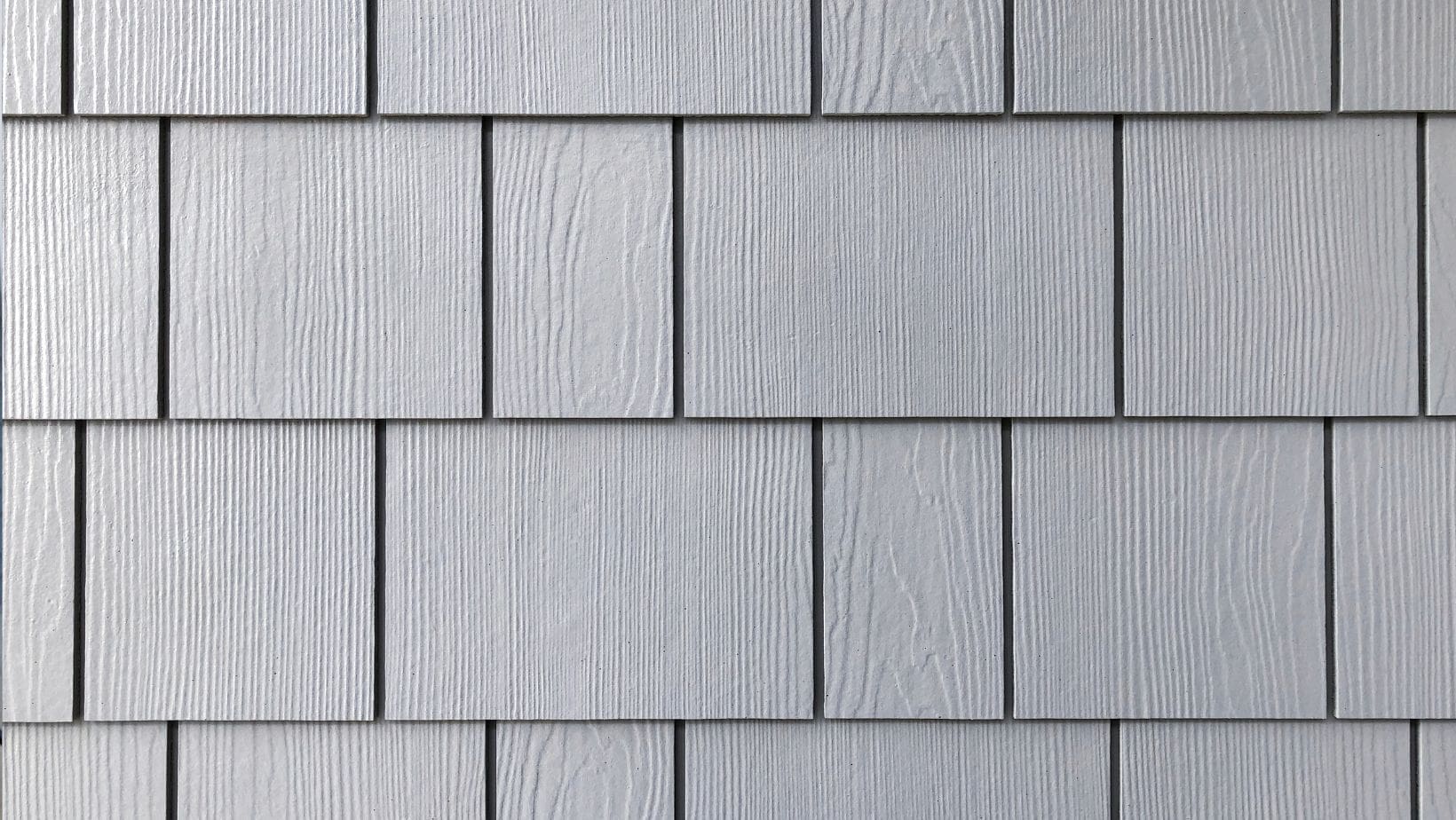 Close-up of gray shake and shingle siding with a wood grain texture, offering a classic and durable exterior finish. Ideal for adding character and weather resistance to homes. Empire Contractors specializes in professional shake and shingle siding installation for a timeless look.
